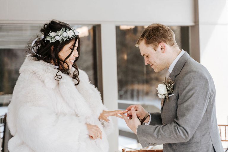 Le marié passant la bague au doigt de sa femme lors de leur mariage d'hiver.